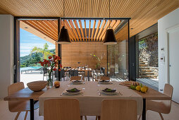 Set table in front of glass wall overlooking terrace of architect-designed house