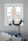 Papierstern und minimalistischer Weihnachtskranz am Fenster