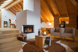 Rustikales Wohnzimmer mit modernen Sesseln und Kaminofen