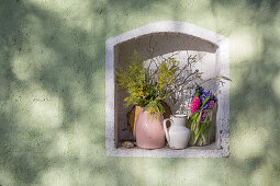 Sträuße aus Mimosen, Hyazinthen und Haselzweigen in Wandnische