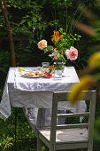 Gedeckter Gartentisch mit Sommerblumenstrauss und Apfelpie auf Teller
