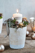 Wintry arrangement of candle and dried flowers in flower pot