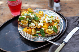 Crostini with yellow tomatoes, peas, mint and feta cheese