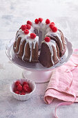 Chocolate wreath cake with sugar icing and raspberries, cut