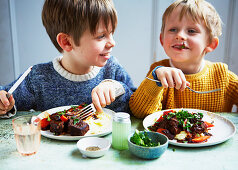 Zwei Jungen essen Rindfleischeintopf (Slow Cooking)
