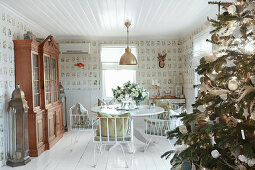 Decorated Christmas tree, round dining table and dresser in rustic interior