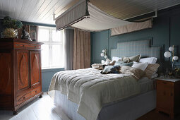 Double bed with canopy and wooden wardrobe in rustic bedroom