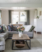 Sofas, coffee table with antique wooden trough and patterned wallpaper in bright living room