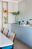 Kitchen counter with marble top next to dining table and bistro chairs