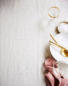 Crockery, golden cutlery and glasses on a crumpled tablecloth