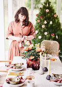 Woman at a festively set table in nude tones for Christmas