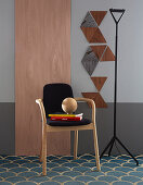 Chair in front of wooden panel next to triangles of wooden veneer on grey wall
