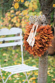 Wreath of maple leaves and clematis seed heads hung on cherry tree