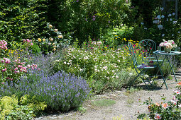 Sitzplatz am Beet mit Rosen, Lavendel, Katzenminze, Frauenmantel und Vexiernelke, kleiner Rosenstrauß als Tischdeko