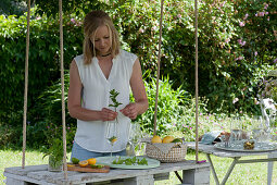 Woman gives orange slice, lime and fresh mint in glasses, hanging palette as table