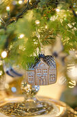 House-shaped Christmas bauble hanging from branch