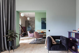 Armchair next to low bookcase and view into dining room