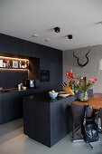 Fitted kitchen and island counter with dark cabinets, dining table and chairs