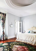 Doppelbett mit hellen Accessoires Teppich mit Blumenmotiv in elegantem Wohzimmer