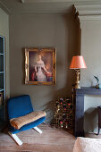 Blauer Polstersessel, Gemälde mit Goldrahmen und Flaschenregal im Schlafzimmer