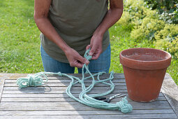 Woman knots blue cords for a macrame hanging basket