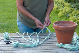 Woman knots blue cords for a macrame hanging basket