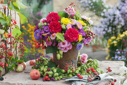 Autumn bouquet with roses, asters, chrysanthemums, hops, rose hips and summer asters in a hop wreath