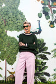 Grauhaarige Frau im grünen Pullover und rosa Hose