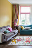 Comfortable sofa and floral rug in living room with yellow walls