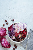 Purple bowl with marinated beetroot, red cabbage, grapes and pomegranate
