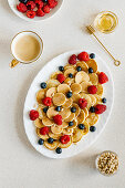 Mini pancakes arranged with berries, pine nuts and agave syrup