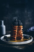 Ein Stapel Kürbis-Pancakes mit Brombeeren und Ahornsirup