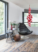 A seating area with a black armchair, a side table and a red-and-white striped decorative object