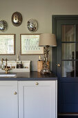 A table lamp with an angel stand next to the sink in a classic grey kitchen