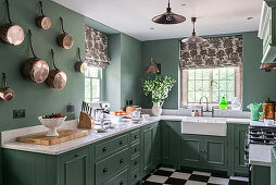 Green paint and copper pots on the wall in 1930s Art Deco-style kitchen