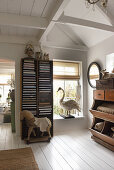 An antique filing cabinet and an antique toy horse in a room with white floorboards