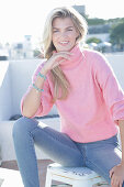 Junge blonde Frau im rosa Rollkragenpullover