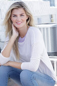 A young blonde woman wearing a purple t-shirt and a white jumper