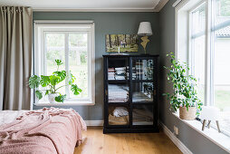 A glass cabinet for bed linen in a bedroom