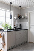 A light grey floor unit with a black granite worktop in front of a window