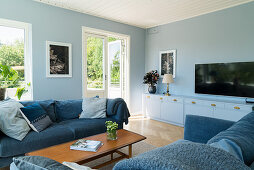 Blaue Sofagarnitur und Lowboard mit Fernseher im Wohnzimmer