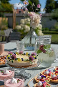 Cakes, tarts and dessert glasses on a table laid on a terrace