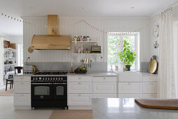 A white kitchen work surface with a gas hob and a brass extractor hood