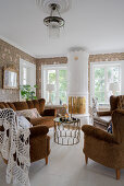 Antique upholstered suite and Swedish tiled stove in the living room with floral wallpaper