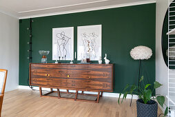 Art prints hanging above a sideboard on a green wall
