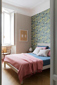 Doppelbett im Schlafzimmer mit Tapete an einer Wand