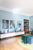 Schwarz-weiße Fotos an blauer Wand über Lowboard in Altbau-Wohnzimmer mit Parkettboden