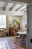 Stone table and chairs in dining area with tiled floor: antique chest of drawers in background