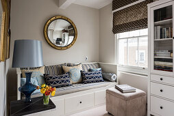 Gold-leaf convex mirror above blue and taupe daybed