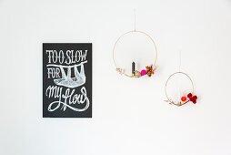 Two golden metal rings with decorations and candles next to motto poster